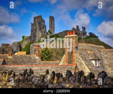 From the famous Bankes Arms Hotel, looking over the lovely stone houses and vibrant red chimney pots of Corfe Castle village to the Castle itself. Stock Photo