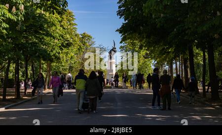 A picture of people walking in the El Retiro Park, with the Fountain of the Fallen Angel. Stock Photo