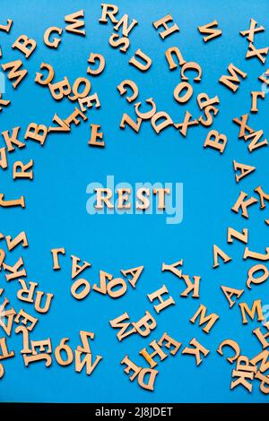 Word REST made out of wooden letters on bright blue background. Motivational Words Quotes Concept. Inspirational phrase Stock Photo