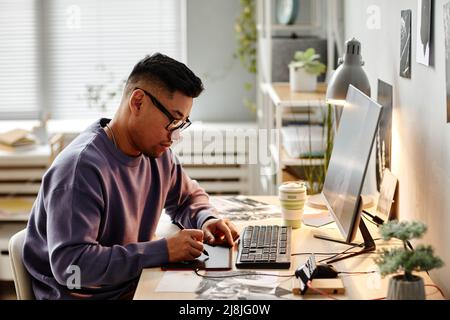 Portrait of Asian male creator retouching photographs at home office workplace and using pen tablet Stock Photo