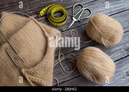 Knitting from wool yarn, scissors and centimeter on wood background Stock Photo