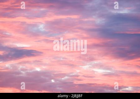 Dramatic red sky at sunset with pink and blue storm clouds. Skyscape pattern, texture or background, UK Stock Photo