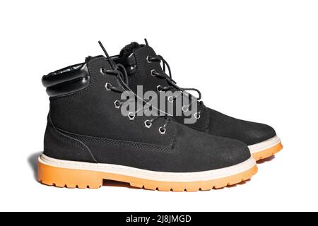Side view of black unisex boots with leather inserts, laces and brown sole isolated on white Stock Photo