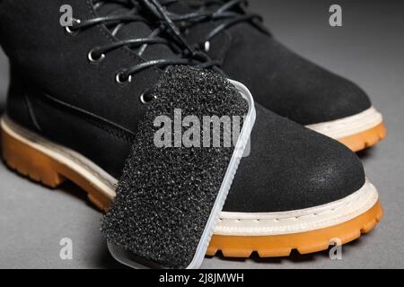 Black hard sponge brush next to suede winter boots Stock Photo