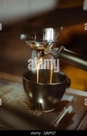 Espresso machine making coffee and pouring in a black cup with steam. Stock Photo