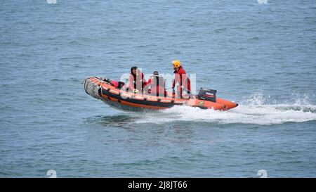 Three lifeguards of the Sécurité Civile (French Civilian Security) sailing in an inflatable boat to rescue people in distress. Stock Photo