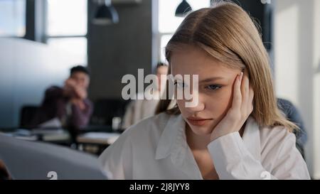 Close-up young caucasian upset girl student sitting alone in classroom at desk suffering from abuse ridicule bad attitude from classmates feels Stock Photo