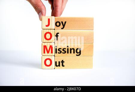 JOMO joy of missing out symbol. Concept words JOMO joy of missing out on wooden blocks on a beautiful white background. Businessman hand. Business JOM Stock Photo