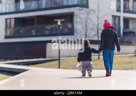 Curly-haired toddler walks with his mom outside full shot copy space . High quality photo Stock Photo