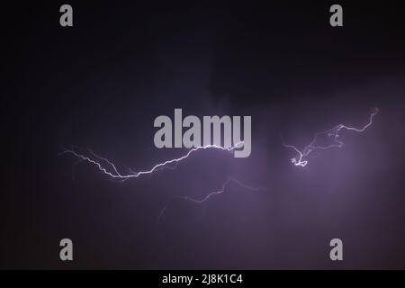 Dark cloudy sky with a dramatic thunder storm and striking lightning bolt strike Stock Photo