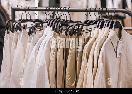 Close-up of hangers with casual youth clothing in store, natural fabrics and colors. Selective focus Stock Photo