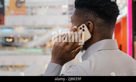 Close-up view from back young african american businessman talking on mobile phone answering business call male manager advising client speaking Stock Photo