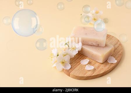 Board with soap bars and flowers on light color background Stock Photo