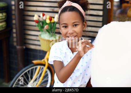 Little African-American girl with cotton candy outdoors Stock Photo