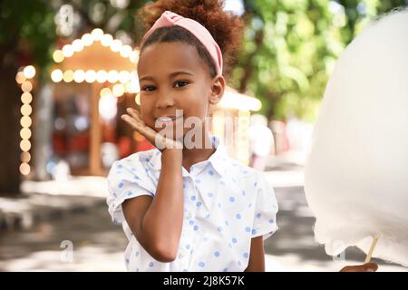 Little African-American girl with cotton candy outdoors Stock Photo