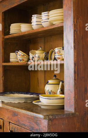 Antique crockery buffet with fine dishes in kitchen inside old circa 1780 French regime cottage style home. Stock Photo