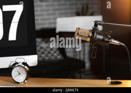 Stand with professional microphone near workplace in dark room Stock Photo