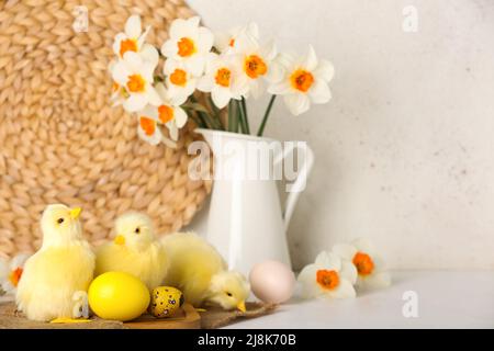 Cute chickens, Easter eggs and flowers on light table Stock Photo