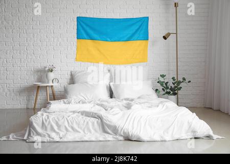 Interior of light bedroom with flag of Ukraine and comfortable bed Stock Photo