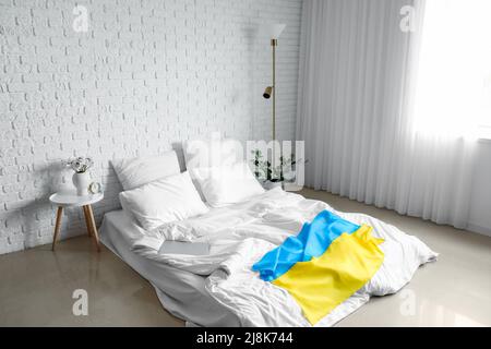 Interior of light bedroom with flag of Ukraine and comfortable bed Stock Photo