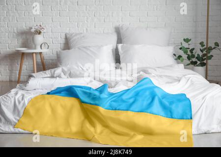 Flag of Ukraine on comfortable bed in light room Stock Photo