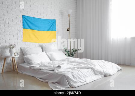 Interior of light bedroom with flag of Ukraine and comfortable bed Stock Photo