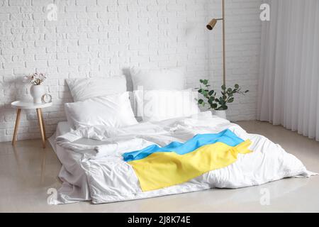 Interior of light bedroom with flag of Ukraine and comfortable bed Stock Photo