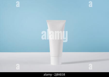 Moisturiser hand cosmetic cream white plastic tube mockup on blue background front view. Blank body and health care beauty product packaging Stock Photo