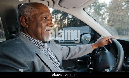 Mature african american happy male driver sits behind wheel automobile smiling enjoys comfortable ride successful businessman buys new car tries out Stock Photo