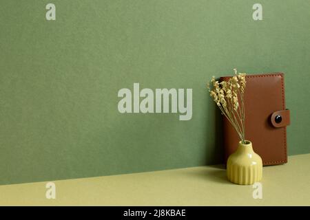 Dairy notebook and dry flower on desk. khaki green background Stock Photo
