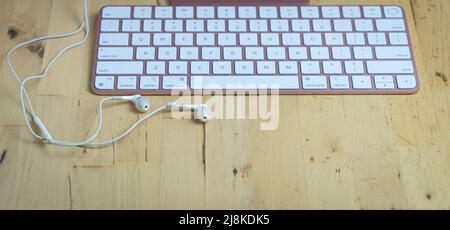 White headphones with keyboard on wood desk. Copy space. Stock Photo