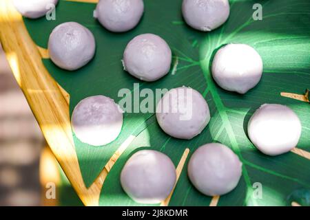 mini purple sweet steaming bun on decorative palm leaf on wood plate in outdoor field. Stock Photo