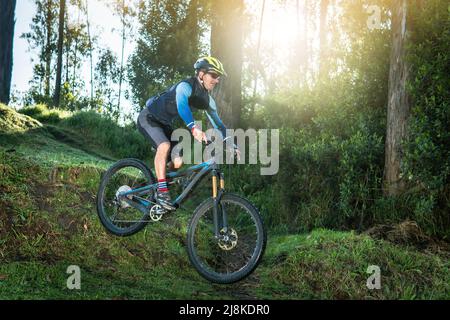 Man jumping in a forest on his mountain bike at sunrise Stock Photo