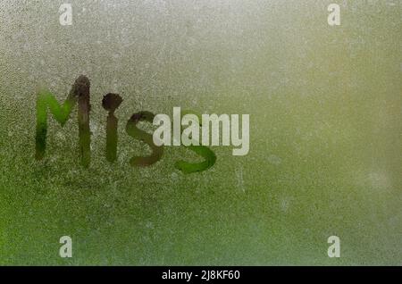 Word writing as Miss on window which fogged up after rain with blurred green color background. Stock Photo