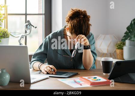 Woman is working in the office and having headache. Concept of small business. Stock Photo
