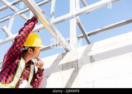 Construction worker or contractor checking house frame, worker roofer builder working on steel roof structure on building  construction site Stock Photo