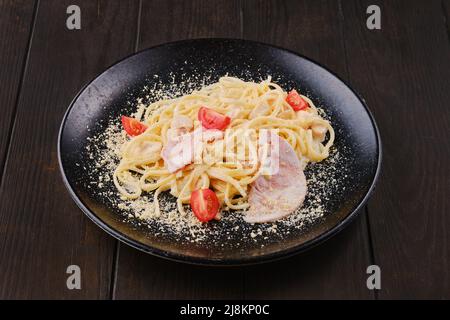 Spaghetti with ham and tomatoes sprinkled with grated parmesan Stock Photo
