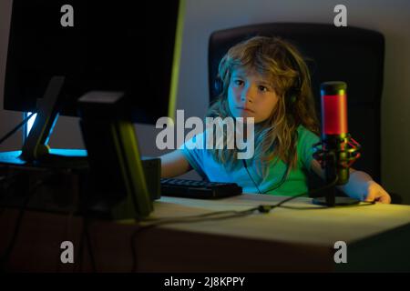 Child plays a video game on the pc computer screen. Gamer play computer games. Neon lighting. Stock Photo