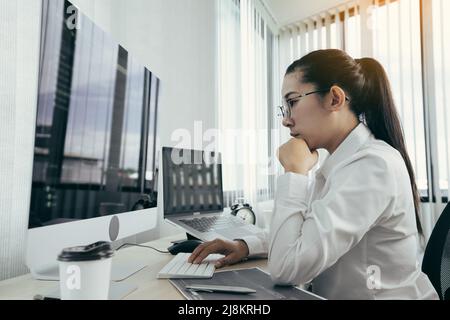 Asian female software developer is worried about analyzing code-based systems at his office. Stock Photo