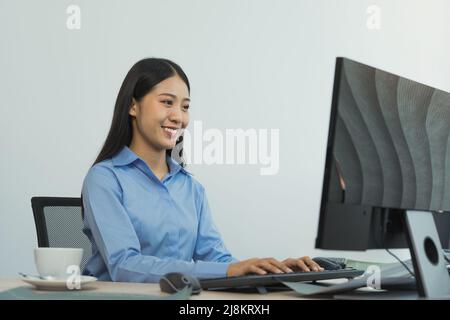 Business woman working on desktop computer monitor professional and sitting at her office desk and working on new software program. Stock Photo
