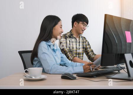 Young asian partner programmers working in team while making a new computer codes on desktop computer in the office. Stock Photo