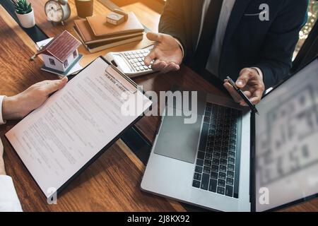 Agents are using pens pointing to blueprint home design on laptop ...