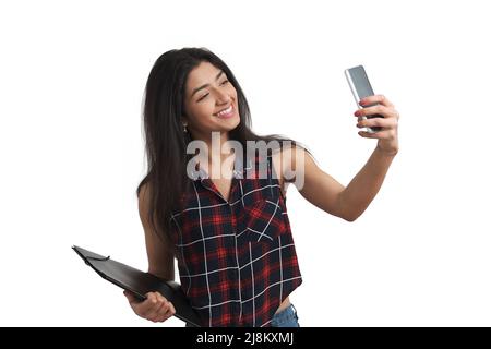 Young Venezuelan student taking a selfie with the phone, isolated. Stock Photo