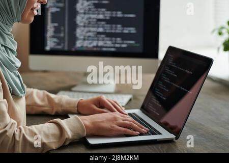 Professional programmer wearing hijab sitting at office table typing ...