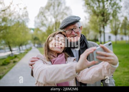 Happy senior man and his adult daughter taking selfie outdoors on a walk in park. Stock Photo
