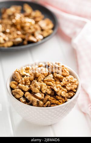 Peeled walnut kernels in bowl on a white table. Stock Photo