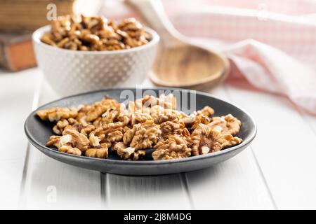 Peeled walnut kernels on plate on a white table. Stock Photo