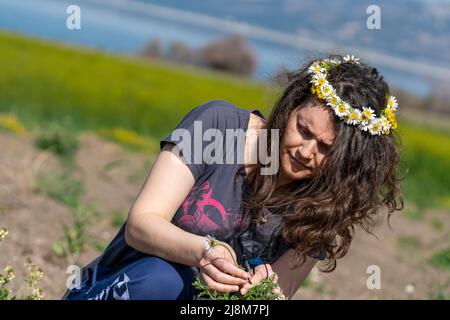 Selective focus shot from opposite profile of woman with crown made of daisy on her head. Stock Photo