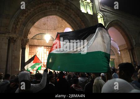 Jerusalem. 16th May, 2022. Palestinians wave Palestinian flags during clashes with Israeli police in Jerusalem on May 16, 2022. Clashes erupted between Palestinians and Israeli police in East Jerusalem on Monday night as thousands gathered for the funeral of a young Palestinian who died after being injured in clashes with police in April. Credit: Muammar Awad/Xinhua/Alamy Live News Stock Photo