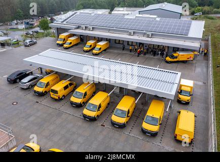 Saxony, Eibenstock: 17 May 2022, Conventional and electrically powered Deutsche Post DHL Group vehicles are parked on the site of a climate-neutral delivery base. The new building offers optimal conditions for processing increasing volumes of parcels and merchandise mail, is also climate-neutral and was ceremoniously handed over on the same day. In addition to underfloor heating with a heat pump, the building has a photovoltaic system that generates a large part of the energy required for daily operations. Any additional energy required to charge the electric vehicles is sourced exclusively as Stock Photo
